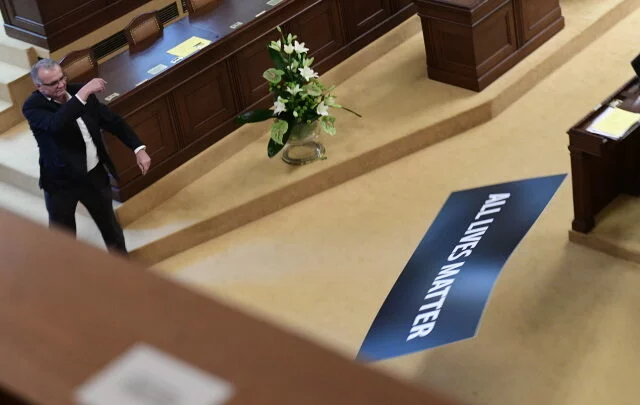 Předseda poslanců TOP 09 Miroslav Kalousek odhazuje ceduli s nápisem All Lives Matter.