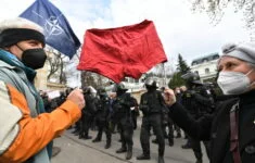 Demonstranti s rudými trenýrkami a policejní těžkooděnci před budovou velvyslanectví Ruské federace.