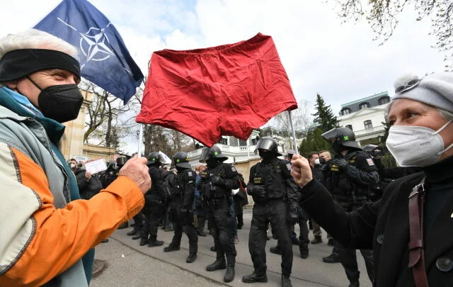 Demonstranti s rudými trenýrkami a policejní těžkooděnci před budovou velvyslanectví Ruské federace.