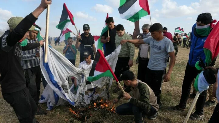 Palestinci pálí vlajku Izraele.