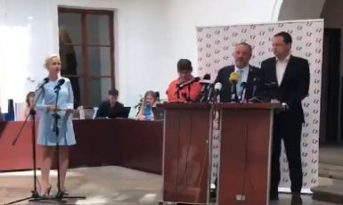 Komunista Pavel Kováčik řečnil za pultem, na jehož čelní stranu mezitím aktivisté promítali záběr z procesu s Miladou Horákovou (Twitter)