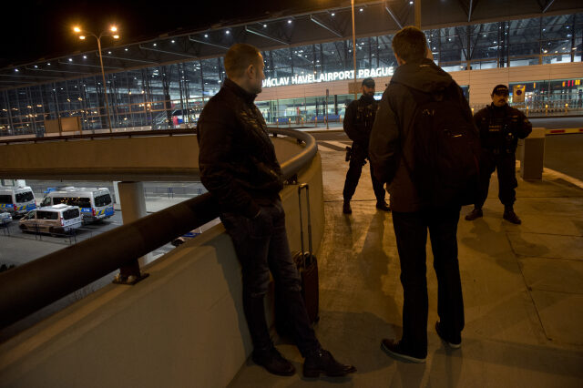Policisté (vzadu) hlídkují na Letišti Václava Havla v Praze, kde 16. února večer oznámil anonymní telefonát uložení bomby na Terminálu 2 (v pozadí). Policie prostor evakuovala, objekt prohlížejí pyrotechnici a psovodi. Z terminálu, který je určen pro lety do zemí schengenského prostoru, dočasně nesmějí odlétat žádná letadla.