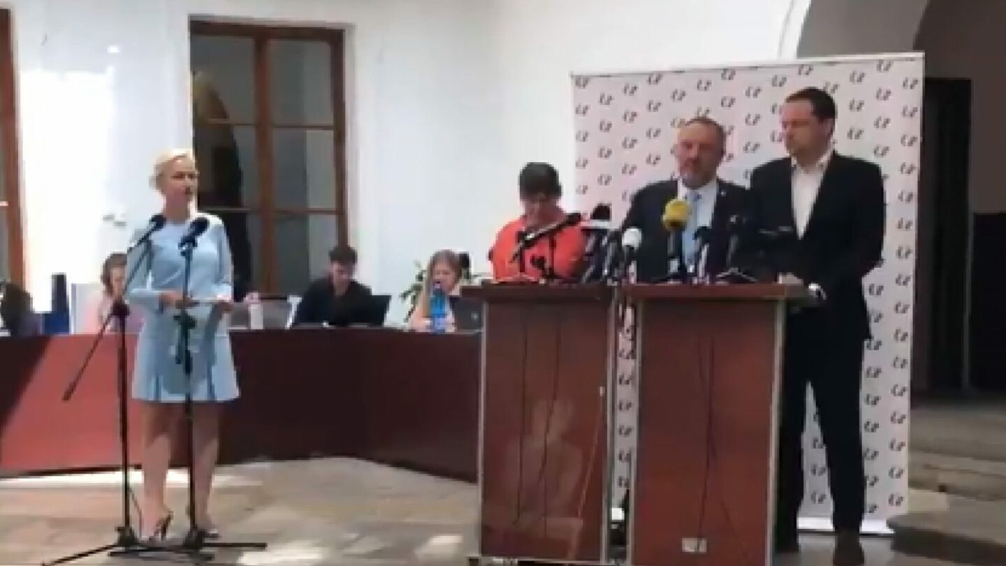 Komunista Pavel Kováčik řečnil za pultem, na jehož čelní stranu mezitím aktivisté promítali záběr z procesu s Miladou Horákovou