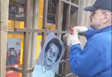 Pracovník ze sídla komunistů odstraňuje portrét oběti komunistů 