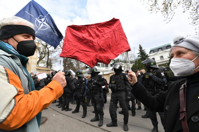 Demonstranti s rudými trenýrkami a policejní těžkooděnci před budovou velvyslanectví Ruské federace.