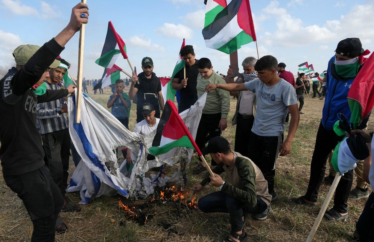 Palestinci pálí vlajku Izraele.